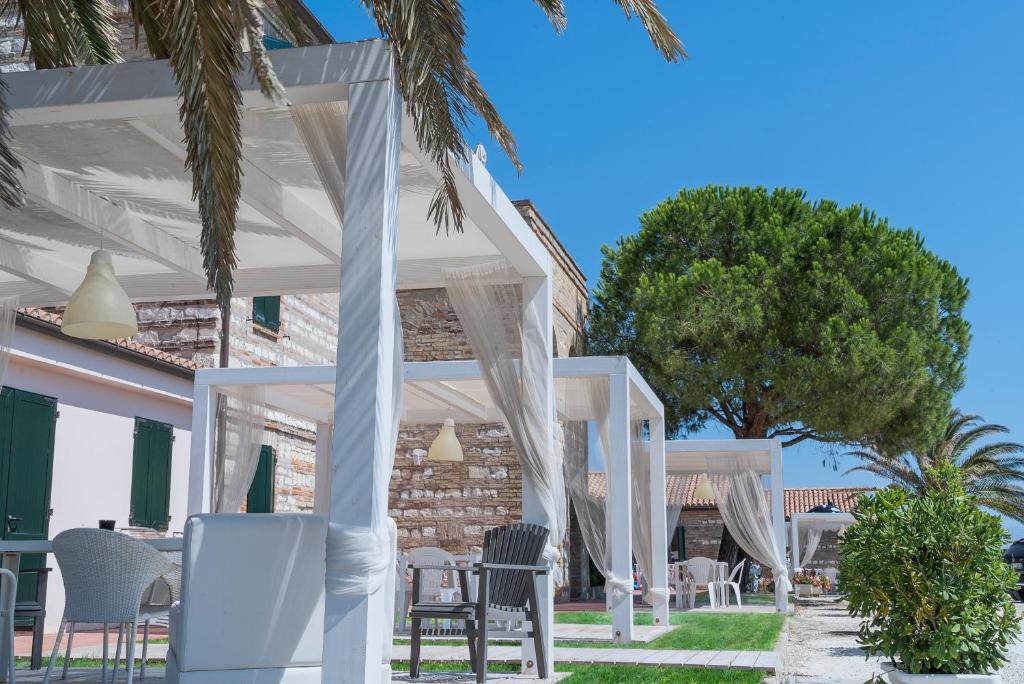 biała pergola z krzesłami i stołami przed domem w obiekcie Lido Azzurro w mieście Numana