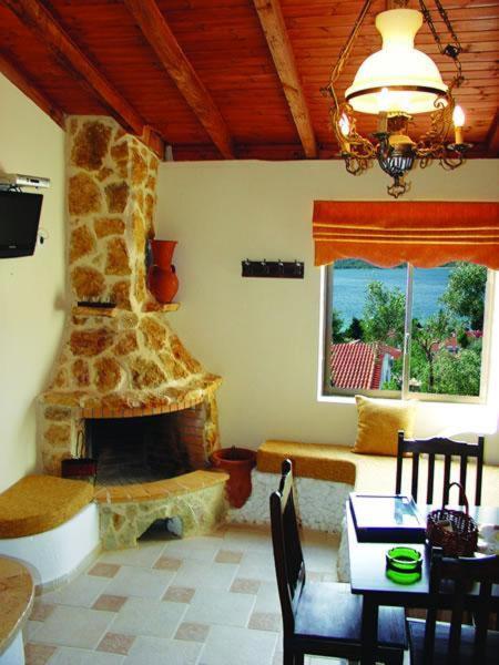 a living room with a stone fireplace and a dining table at Mantas Bay in Vouliagmeni Lake