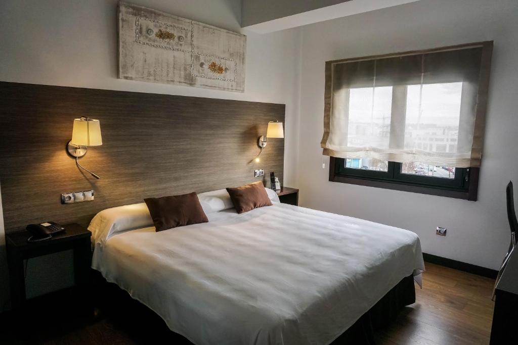 a bedroom with a large white bed and a window at Suites Coruña in A Coruña