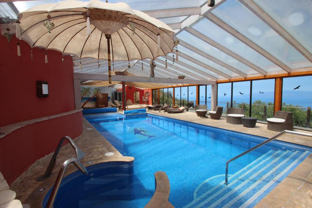 a swimming pool with an umbrella in a building at Finca Montimar Teneriffe in Chio (Guia de Isora) bis 43 Personen in Chío