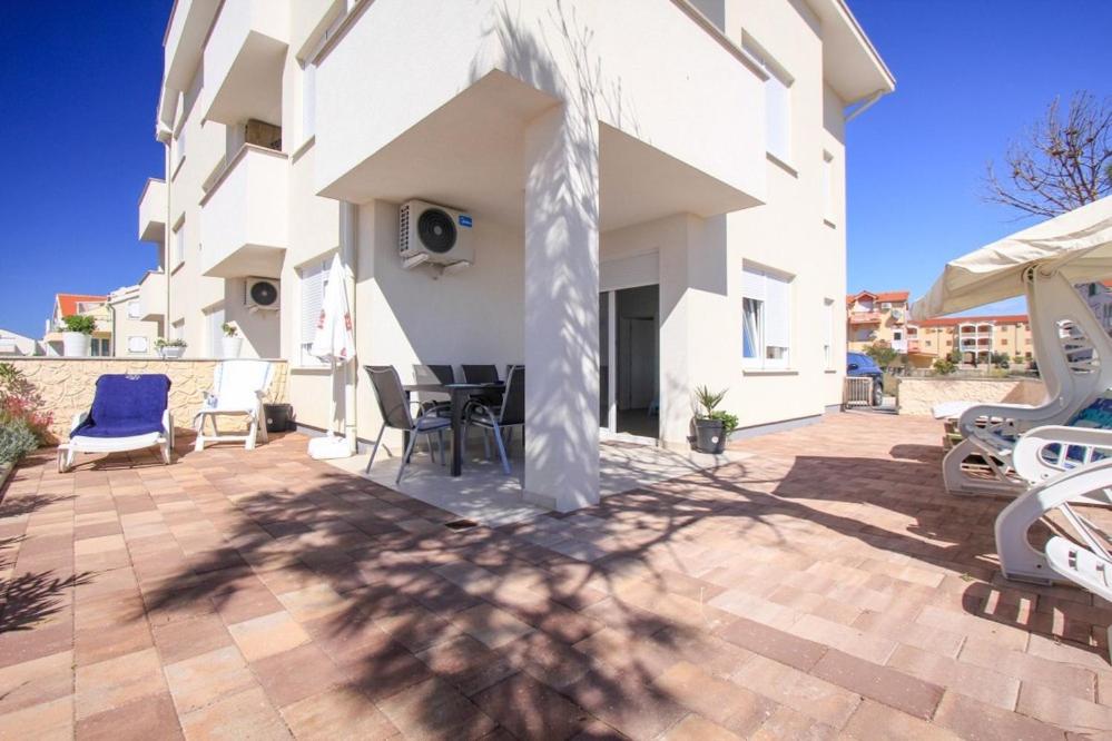 un patio avec une table et des chaises et un bâtiment dans l'établissement Apartment BLUE, à Povljana