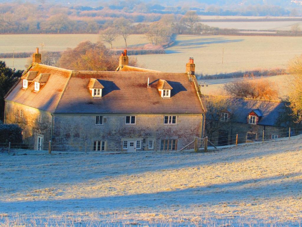 uma casa velha num campo na neve em Cools Farm B&B + Cottages em East Knoyle