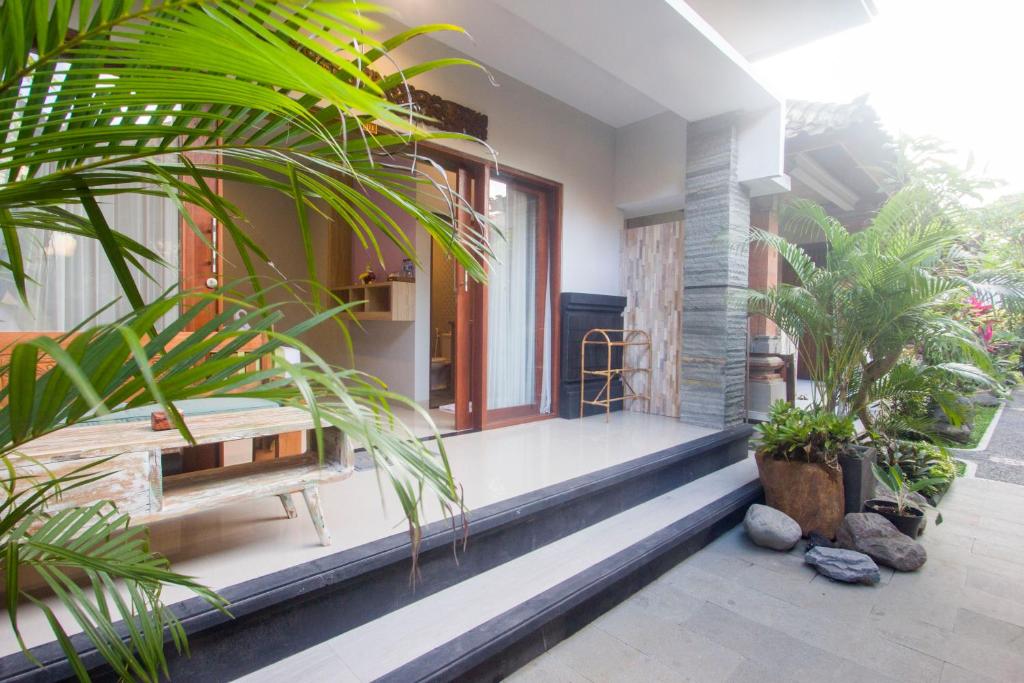 um alpendre de uma casa com um banco e plantas em Nang Ade House em Ubud