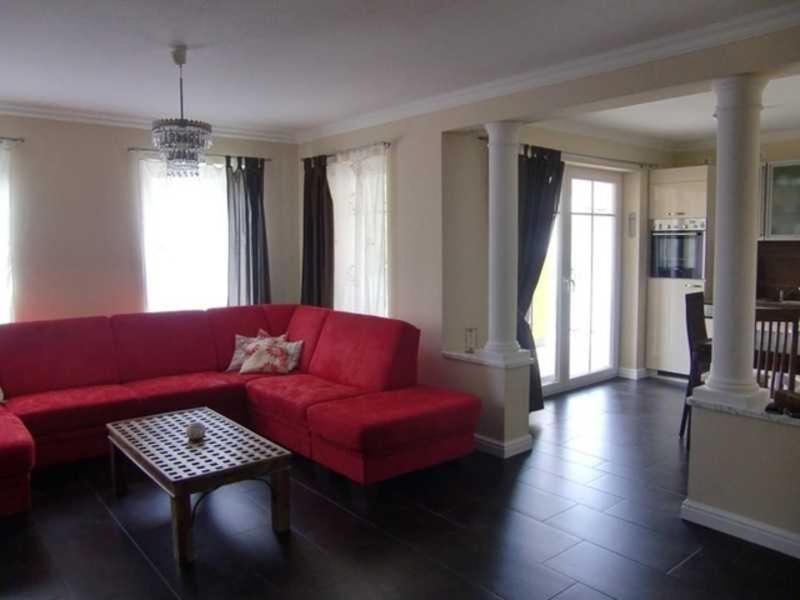 a living room with a red couch and a table at Fewo Ostseetraum_JAeHN in Ostseebad Karlshagen