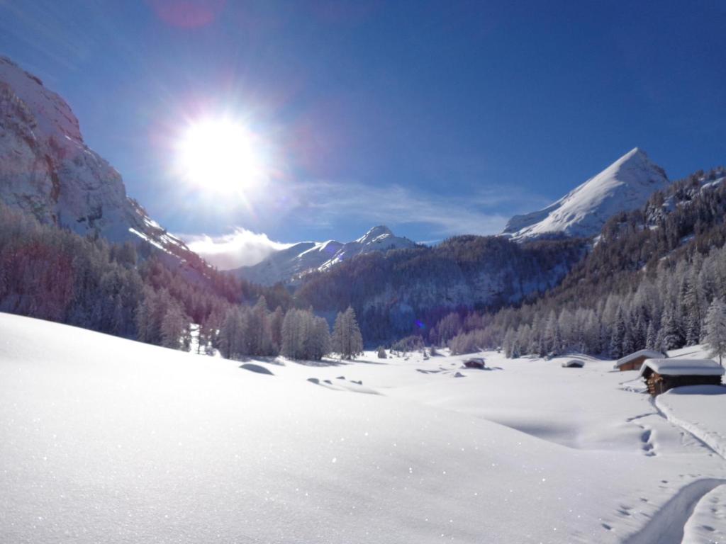 uma montanha coberta de neve com o sol no céu em Hotel Albe em Rocca Pietore
