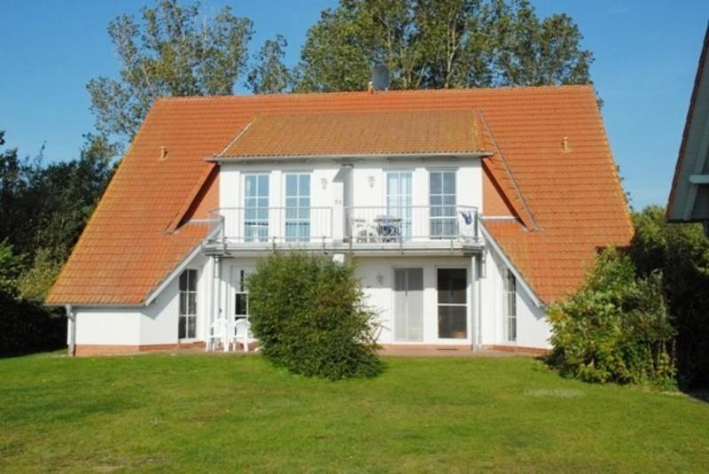 a large white house with an orange roof at Fewo Peenewiesen_SCHAe in Ostseebad Karlshagen