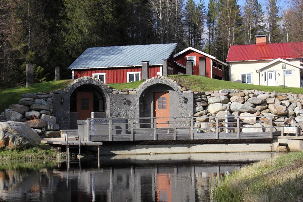een rood huis met een brug over een waterlichaam bij Päärakennus in Karijoki