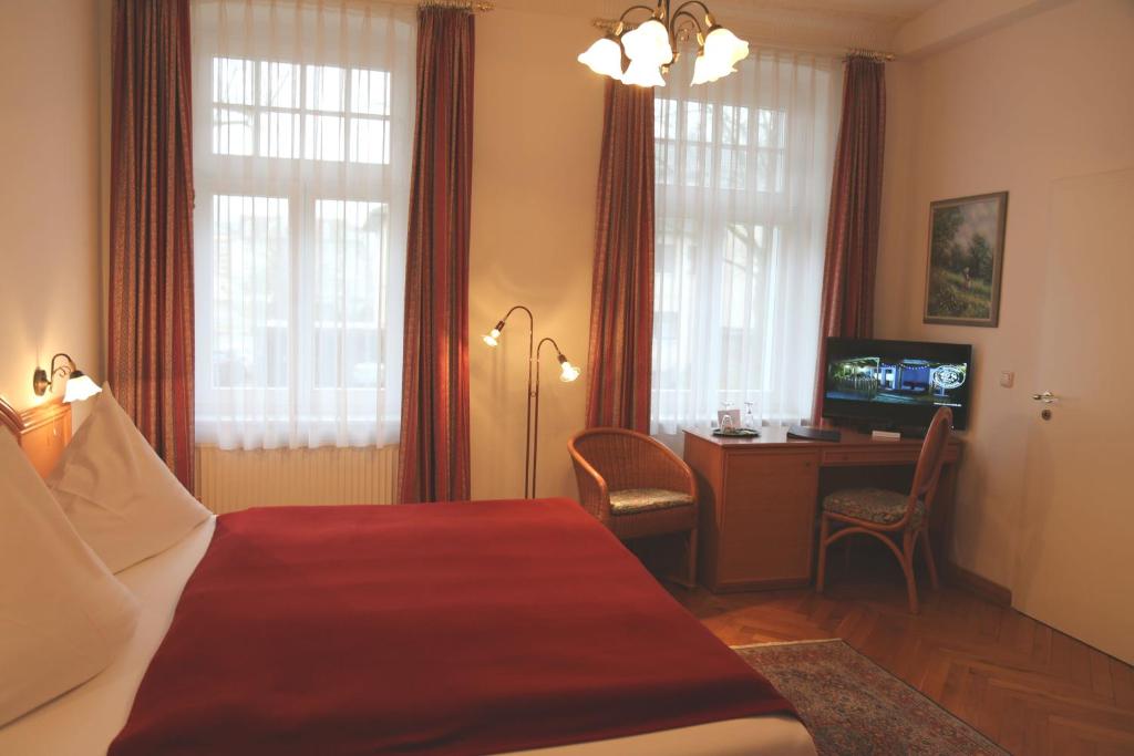シュトラールズントにあるPension Villa Beerのベッド、デスク、テレビが備わるホテルルームです。