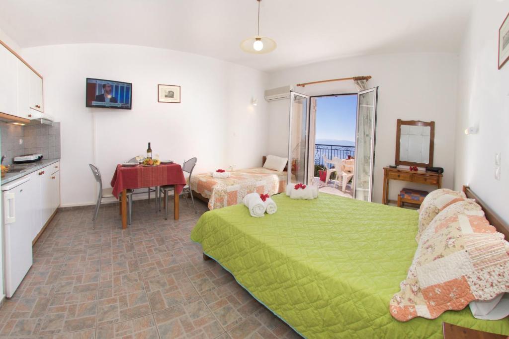 a bedroom with a green bed and a kitchen and a table at Summer Dream in Vlachata