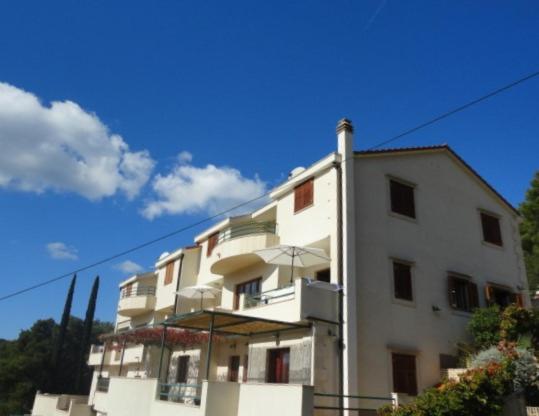 a white building with an umbrella in front of it at Belic Vinko- house in Jelsa