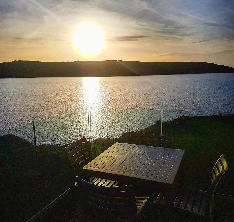 a table and chairs with a view of a lake at The Cliff Hotel & Spa in Cardigan
