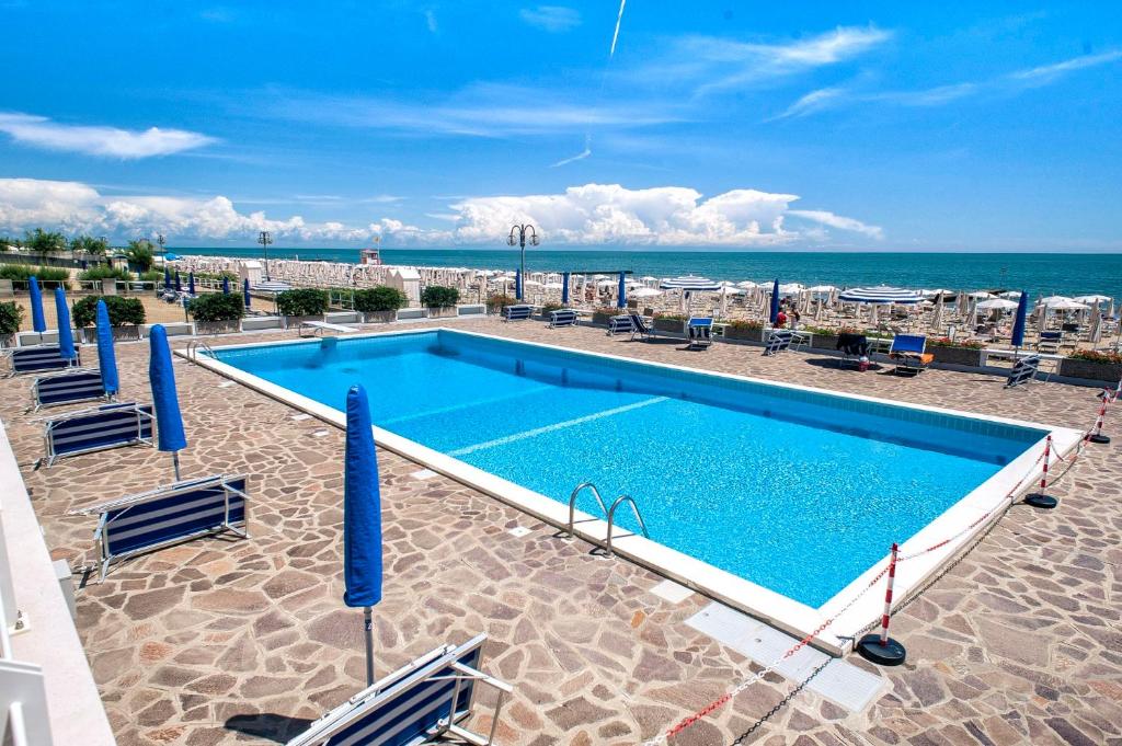 uma piscina com cadeiras e o oceano ao fundo em Sea view apartment with swimming pool em Lido di Jesolo