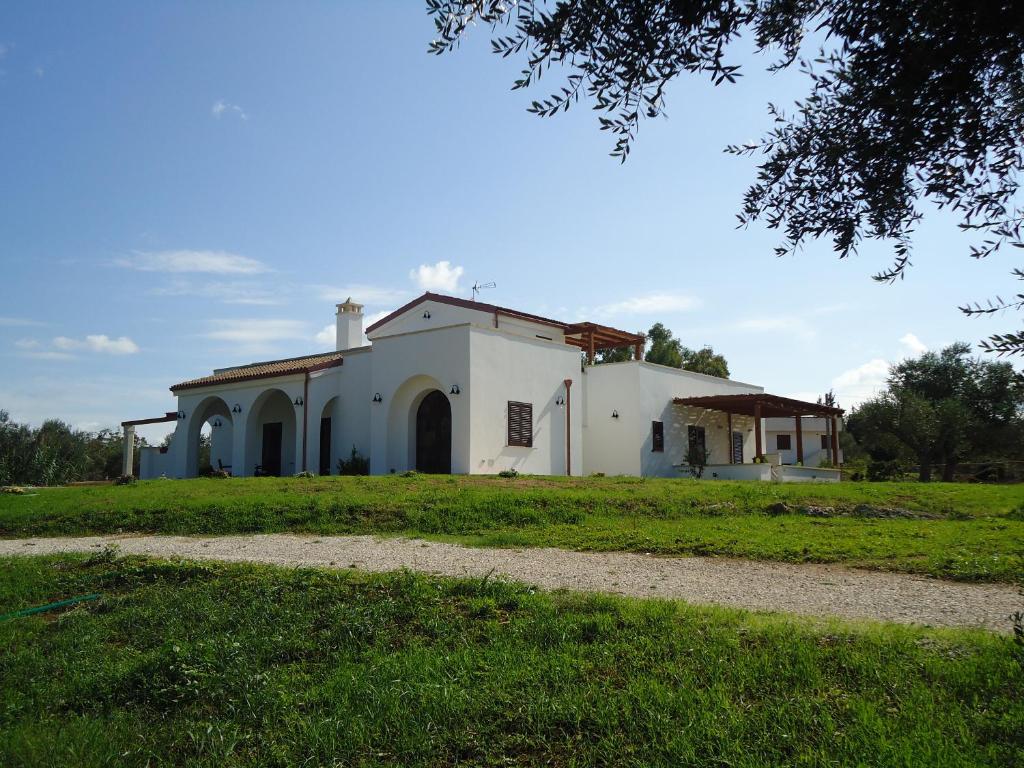 una casa blanca con un campo de hierba delante de ella en Villa Elia - Tenuta Le Scerze - Salento Homes en Borgagne