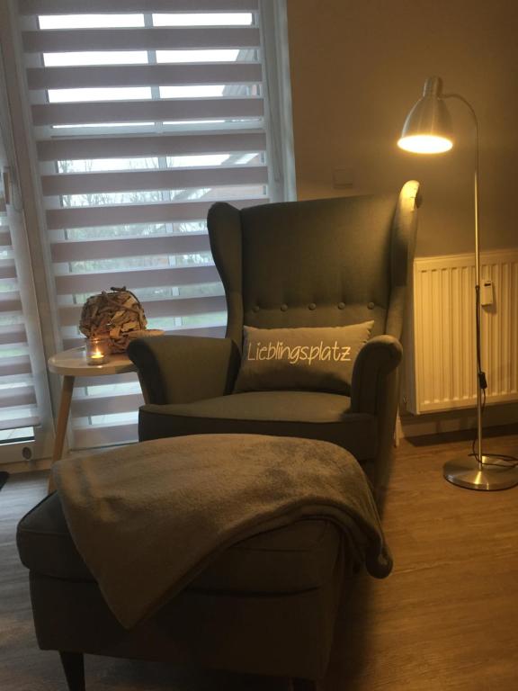 a living room with a couch and a chair and a lamp at Küstenzauber in Schönhagen