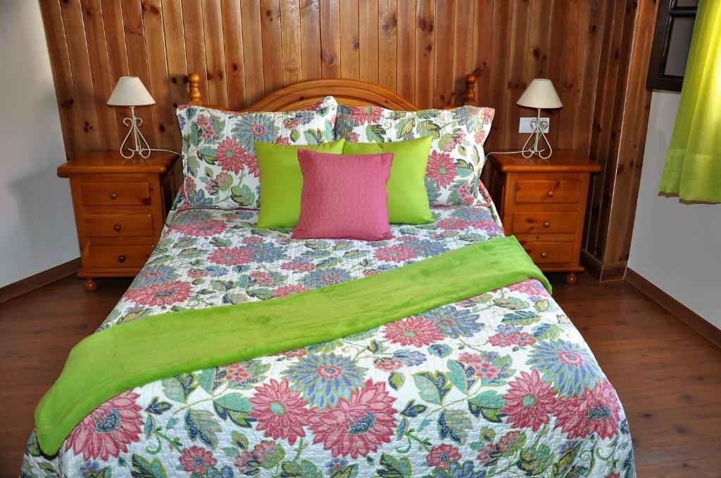 een bed met groene en roze kussens erop bij Casa Teresa Las Vegas in Valsequillo