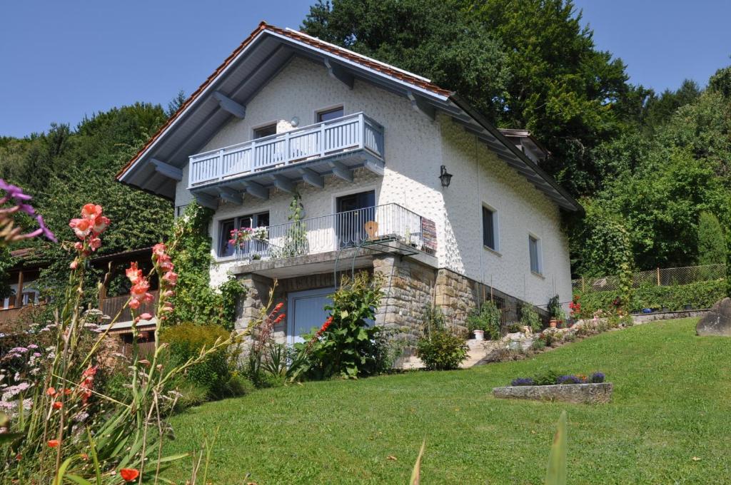 a house with a balcony and a yard at Ferienwohnung Regentalblick in Miltach