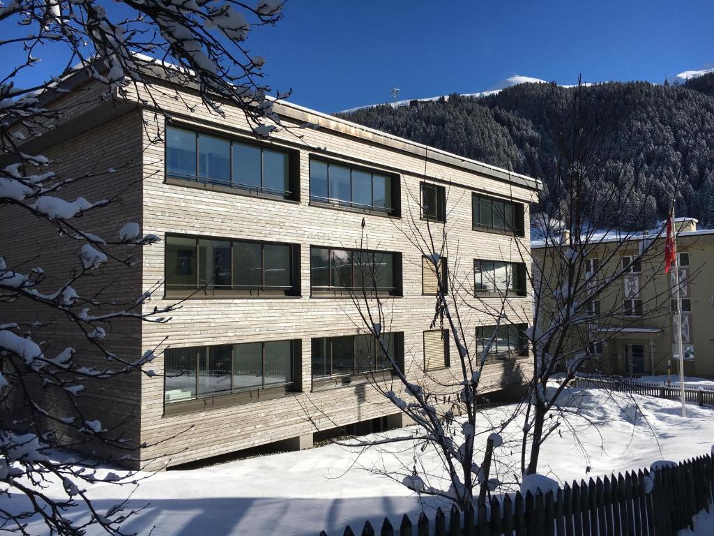 a building in the snow in front of a mountain at Apartment Roccabella in Davos
