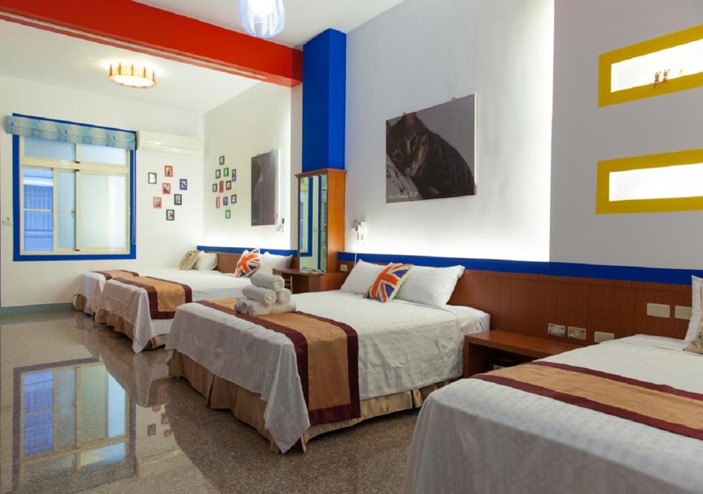 東港的住宿－東港許願宿民宿，拥有蓝色和白色墙壁的客房内的三张床