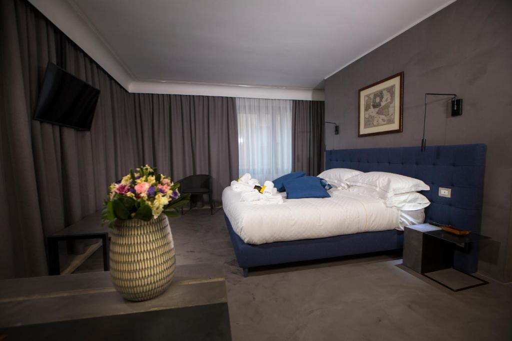 ein Hotelzimmer mit einem Bett und einer Vase aus Blumen in der Unterkunft Principessa Mafalda in Messina