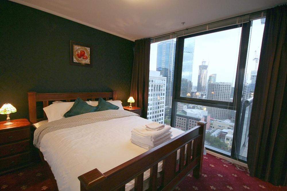 - une chambre avec un lit et une grande fenêtre dans l'établissement CityPoint - Melbourne, à Melbourne