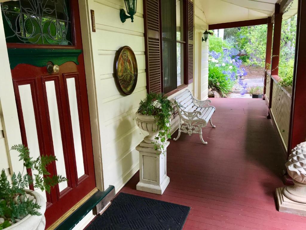 a porch with two benches and a plant in a vase at The Chalet Guesthouse And Studio in Medlow Bath