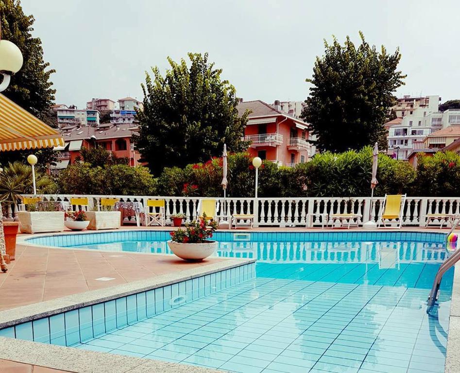 a large swimming pool with a white fence around it at Hotel Arcobaleno in Celle Ligure