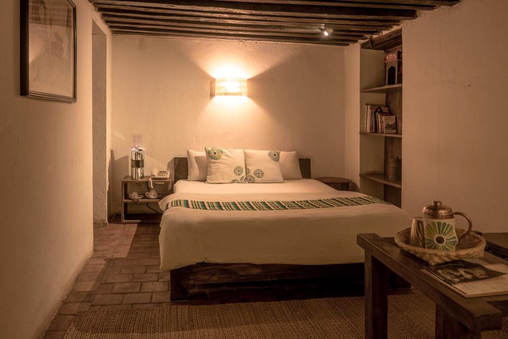 a bedroom with a bed and a table with a lamp at Peacock Guest House in Bhaktapur