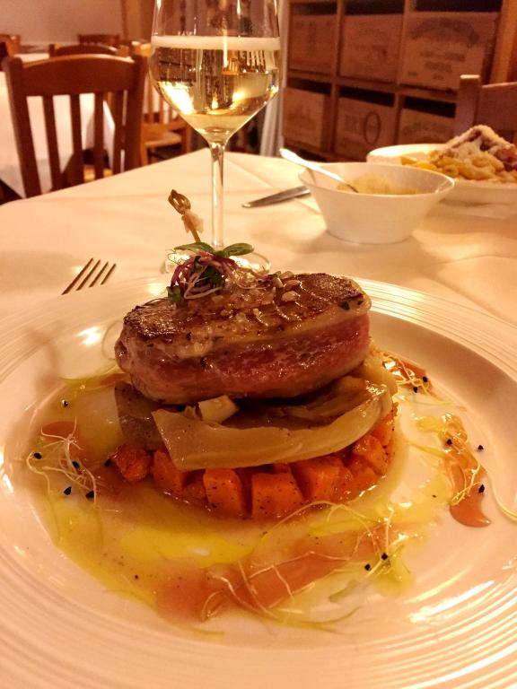 a plate of food on a table with a glass of wine at Le Rocher Hotel in Champoluc