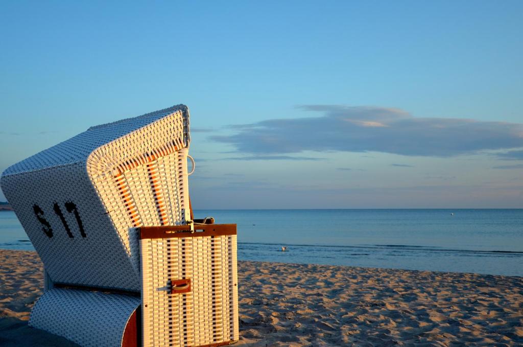 ボルテンハーゲンにあるStrandvilla Waldhausの籐の椅子とスーツケースがビーチに座っている