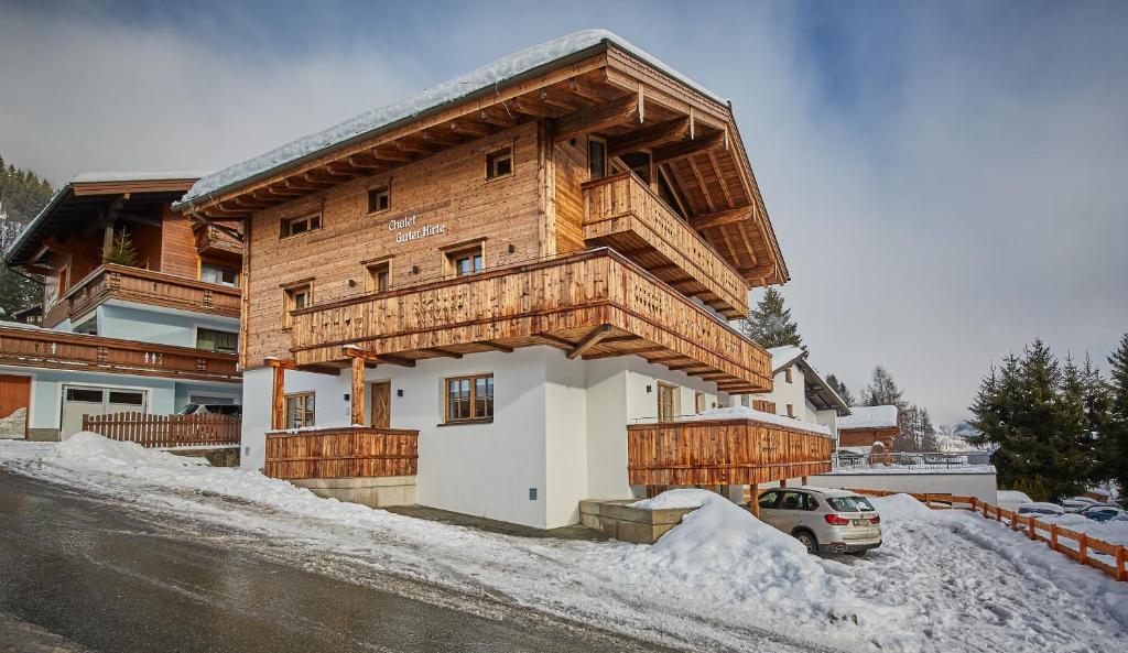 a large wooden house with a car parked in the snow at Chalet Guter Hirte in Saalbach Hinterglemm