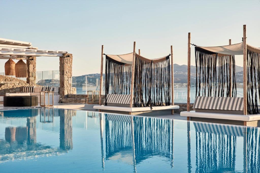 a pool with chairs and a view of the water at Mykonos No5 Luxury Suites & Villas in Ornos