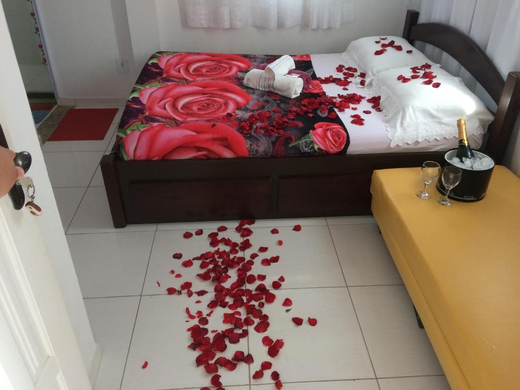 1 dormitorio con 1 cama con rosas rojas en el suelo en Suítes da Erô, en Arraial do Cabo