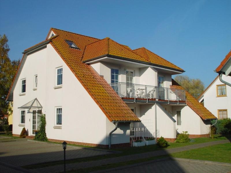 een groot wit huis met een oranje dak bij Fewo Sommergarten 4002_LUCI in Ostseebad Karlshagen