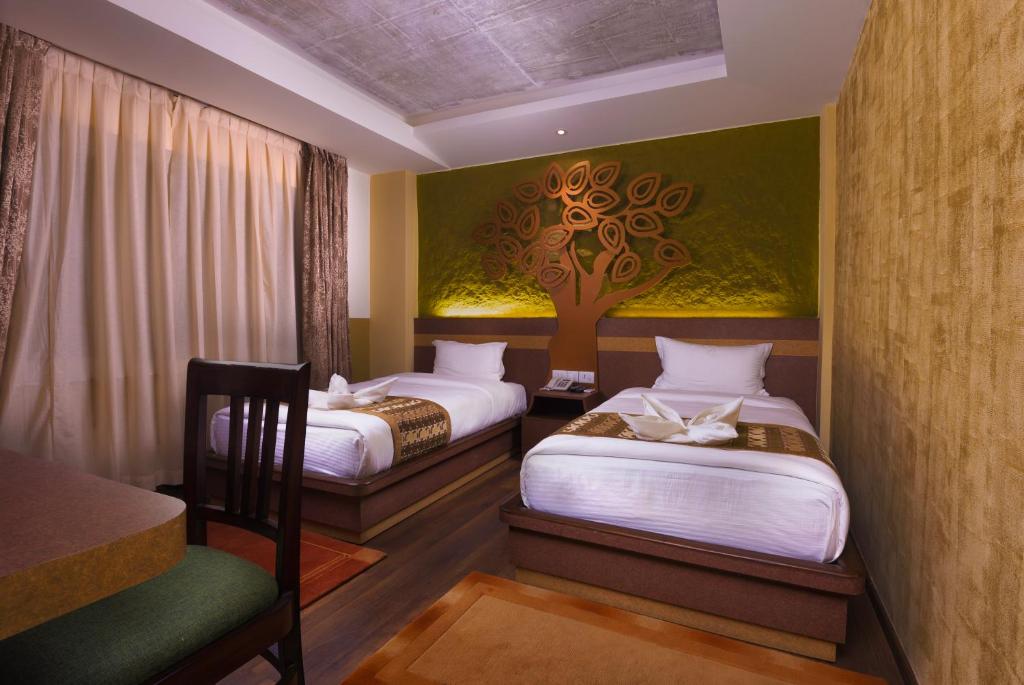 2 Betten in einem Zimmer mit einem Wandbaum in der Unterkunft Bodhi Boutique Hotel in Kathmandu