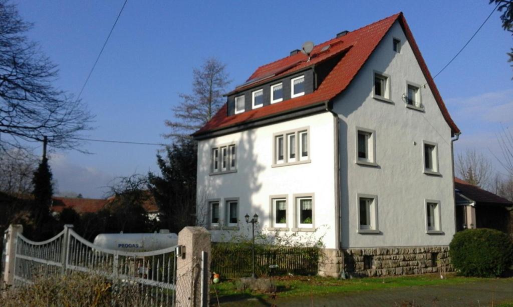 ein weißes Haus mit rotem Dach in der Unterkunft Ferienwohnungen am Schwanenteich in Mühlhausen