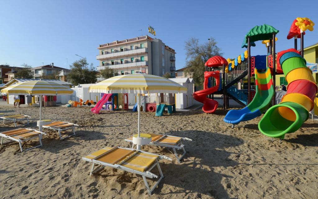 a playground with chairs and umbrellas on a beach at Hotel Rex in Senigallia