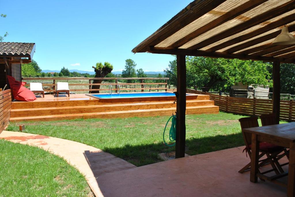 een achtertuin met een zwembad en een houten pergola bij Appartamento Lux in Pasturana