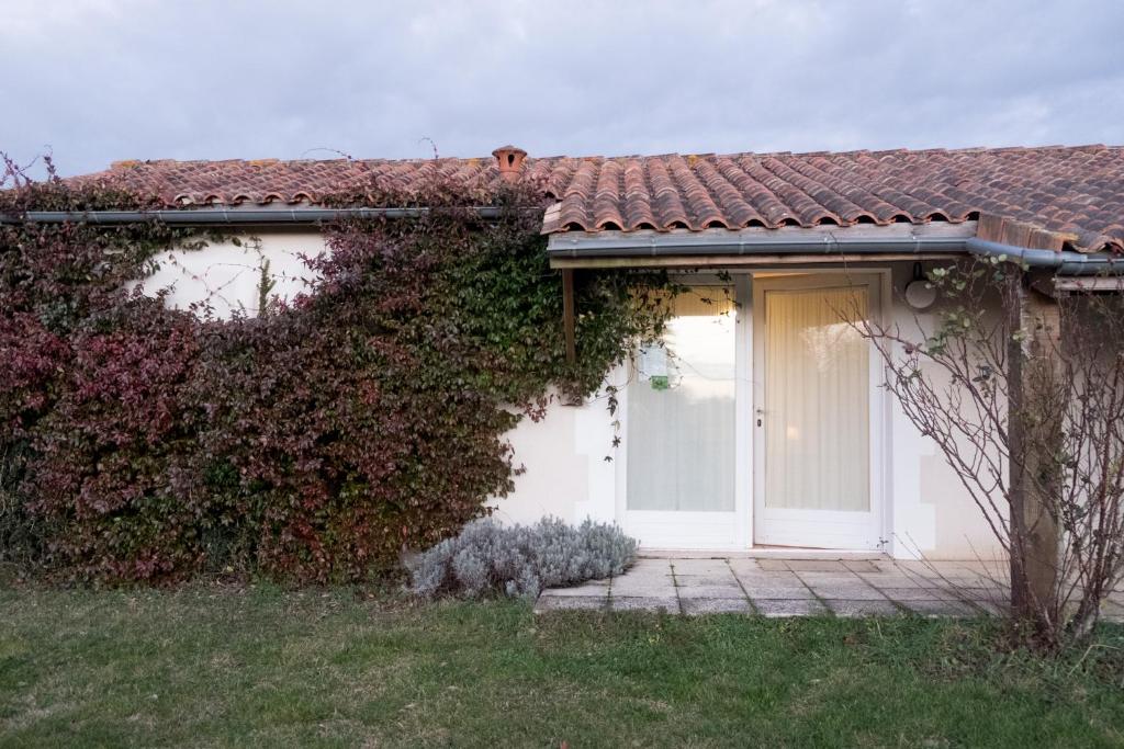 a house with a white door and a hedge at La Bribaudonnière in Saint-Palais-de-Phiolin