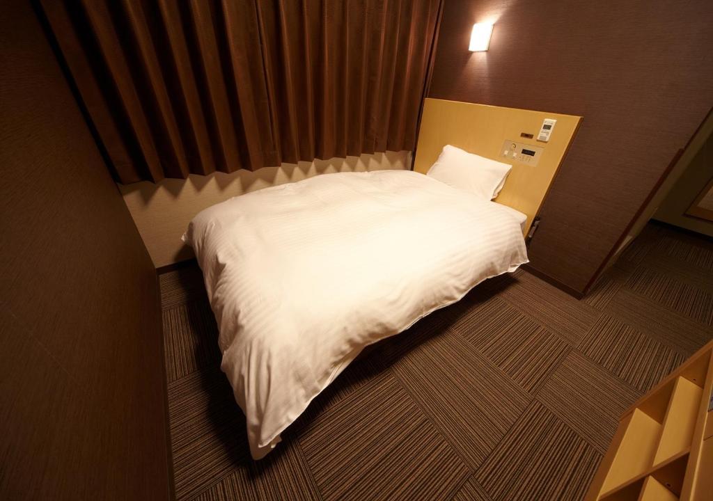 a large white bed in a small room at Dormy Inn Hiroshima in Hiroshima