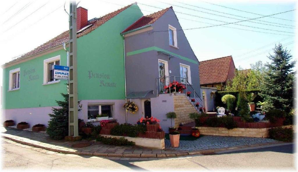 une grande maison verte et violette avec des fleurs devant elle dans l'établissement Pension Renate Braun, à Gamstädt