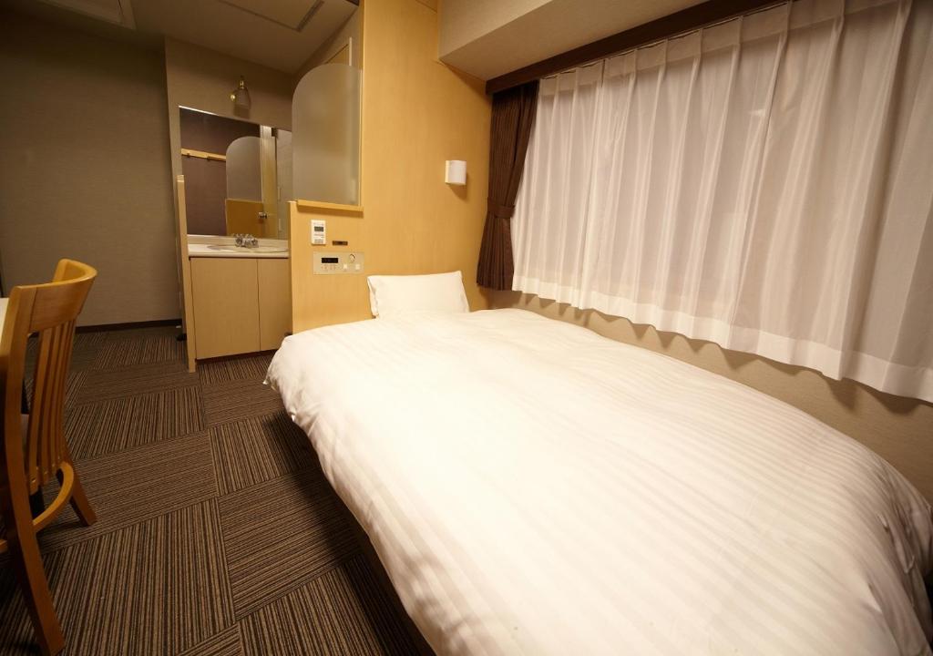 Postel nebo postele na pokoji v ubytování Dormy Inn Hiroshima