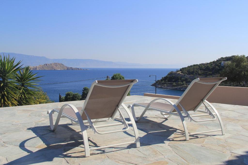 two chairs sitting on a patio overlooking the ocean at Alexander Villa Pefkali in Pefkali