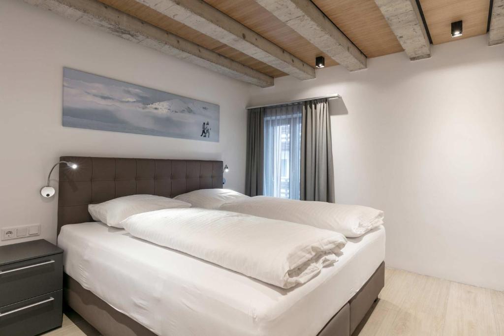 Schlafzimmer mit einem Bett mit weißer Bettwäsche und einem Fenster in der Unterkunft Doris' Nest in Kitzbühel