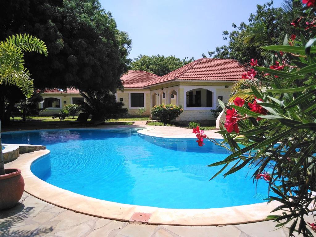 a swimming pool in front of a house at Safina Cottages in Diani Beach