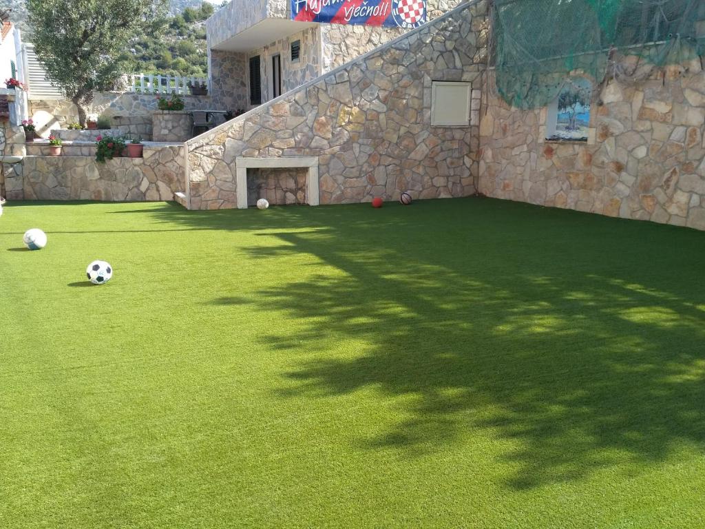 a green yard with soccer balls on the grass at Apartment Igralište Mirakul in Seget Vranjica