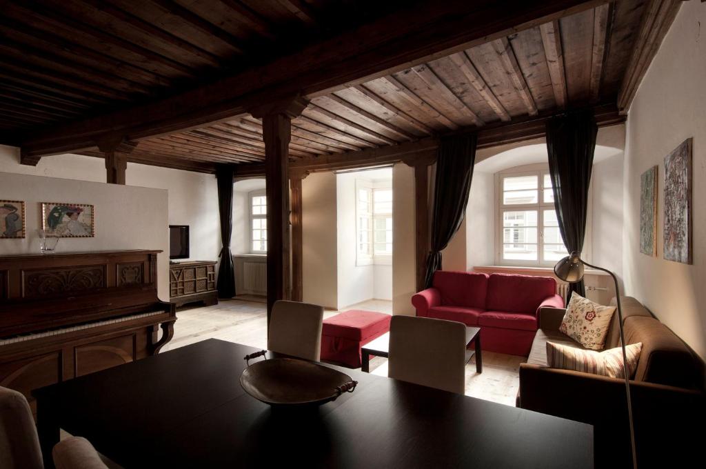 ein Wohnzimmer mit einem Tisch und einem roten Sofa in der Unterkunft Residence Fink Central Apartments in Bozen