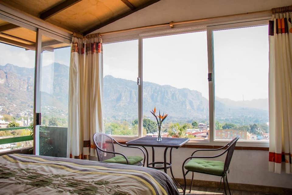 a bedroom with a table and chairs and windows at Posada Paraiso in Tepoztlán