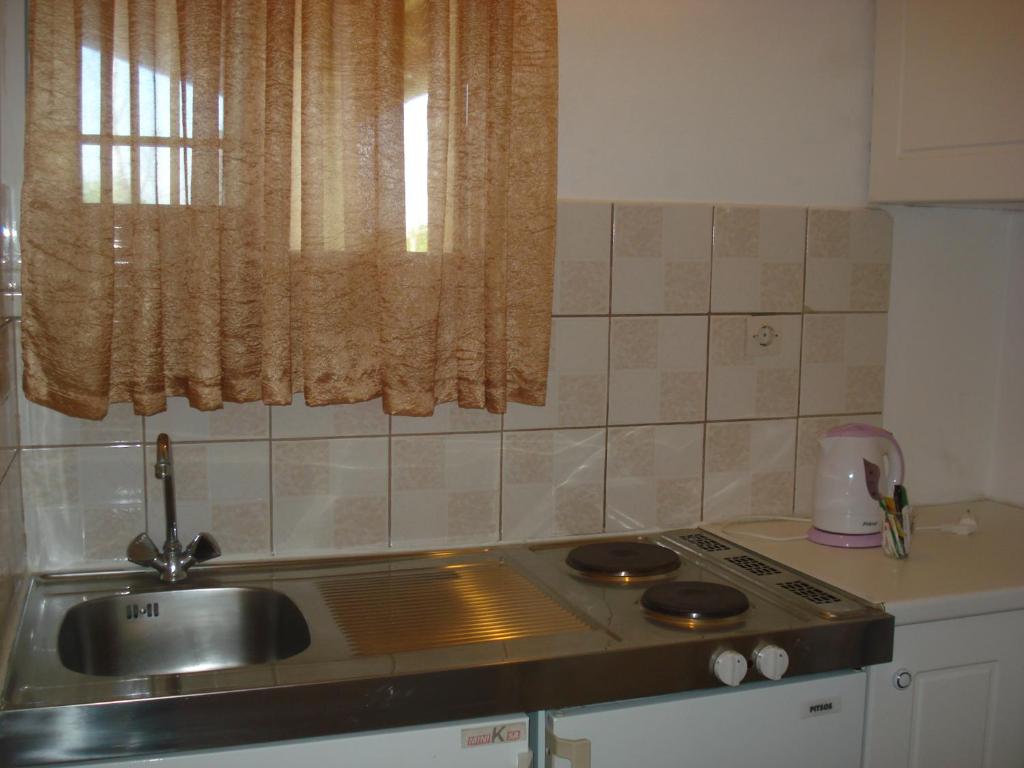 eine Küche mit einer Spüle, einem Herd und einem Fenster in der Unterkunft Iron House in Agios Georgios