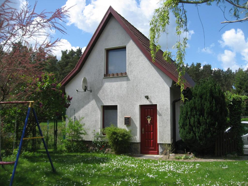 una piccola casa bianca con una porta rossa di Ferienhaus Moni a Waren