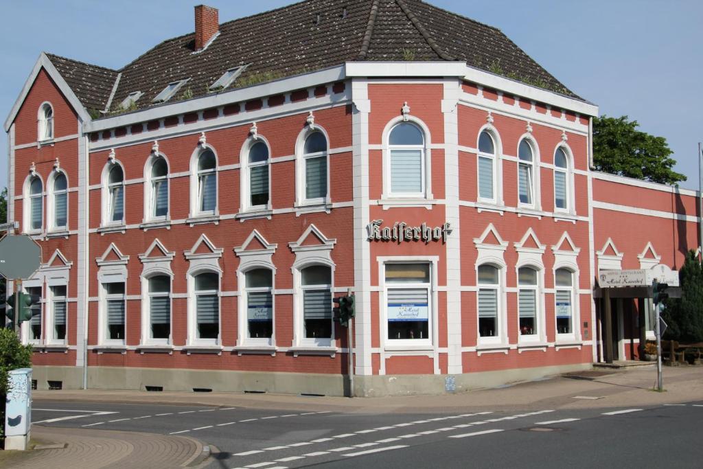 a large red brick building on the corner of a street at Hotel Kaiserhof in Munster im Heidekreis